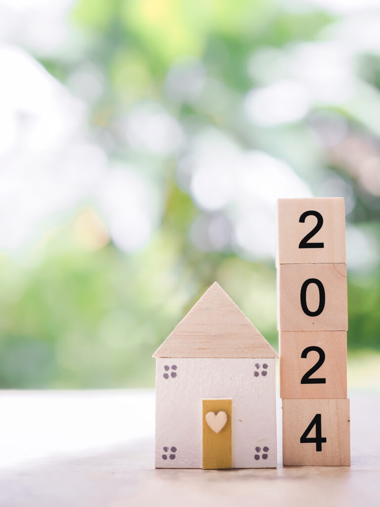 Wooden block house with wooden blocks spelling out 2024 next to it.